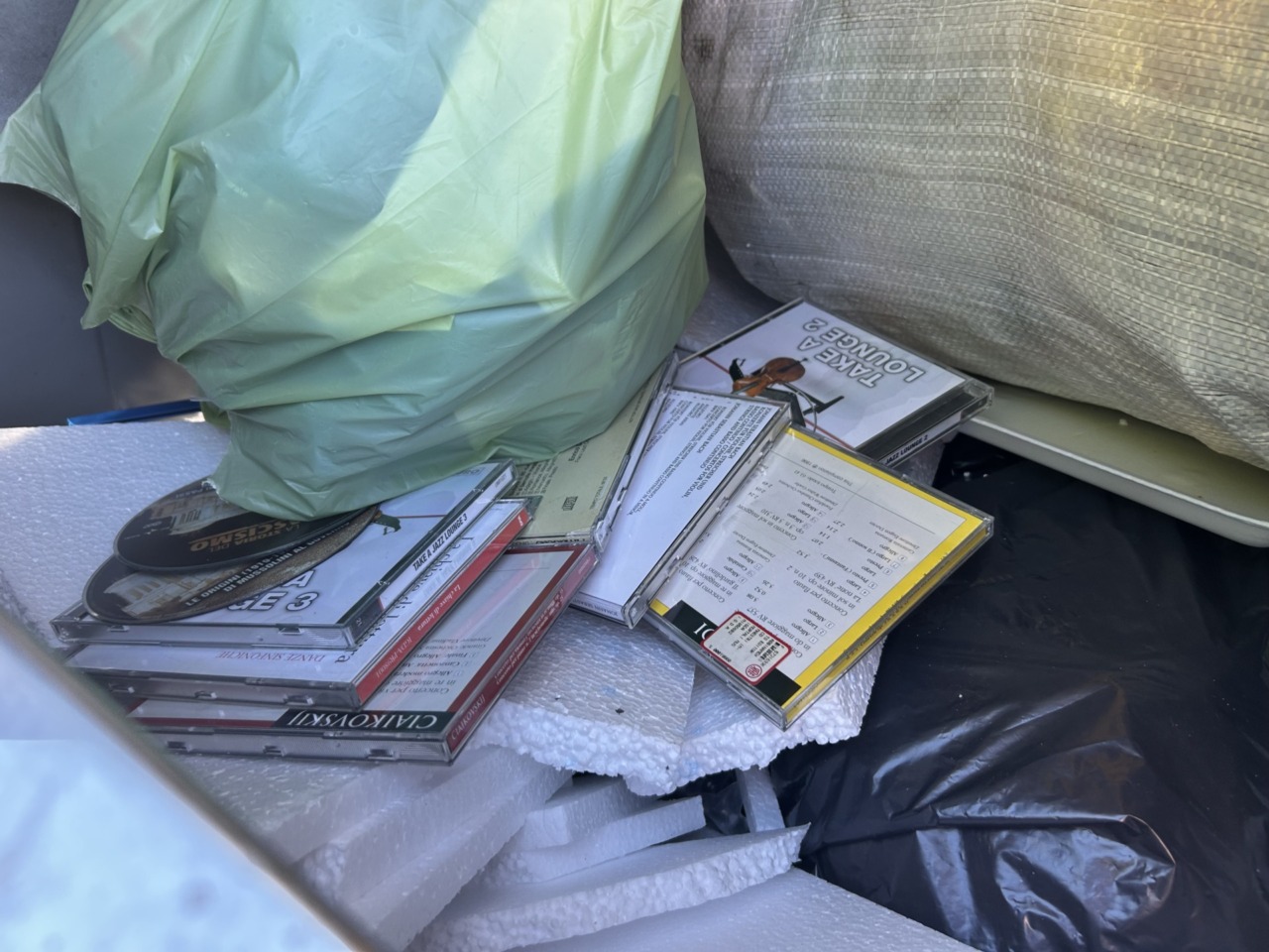 A pochi passi dal centro, una collezione di CD musicali abbandonata nei bidoni della plastica