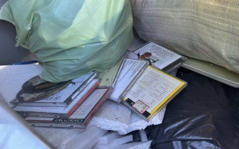 A pochi passi dal centro, una collezione di CD musicali abbandonata nei bidoni della plastica